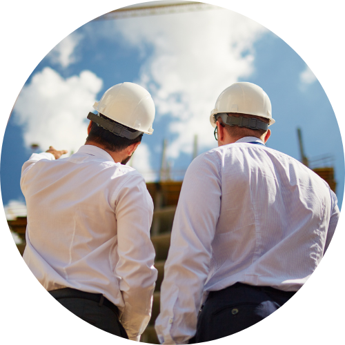 2 men wearing white hard hats pointing at a construction work site